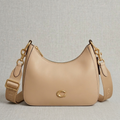 Coach Small Jonie 22 half-moon leather shoulder bag in a neutral color.