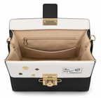 black and white top-handle satchel bag with a shoulder strap and gold-tone hardware