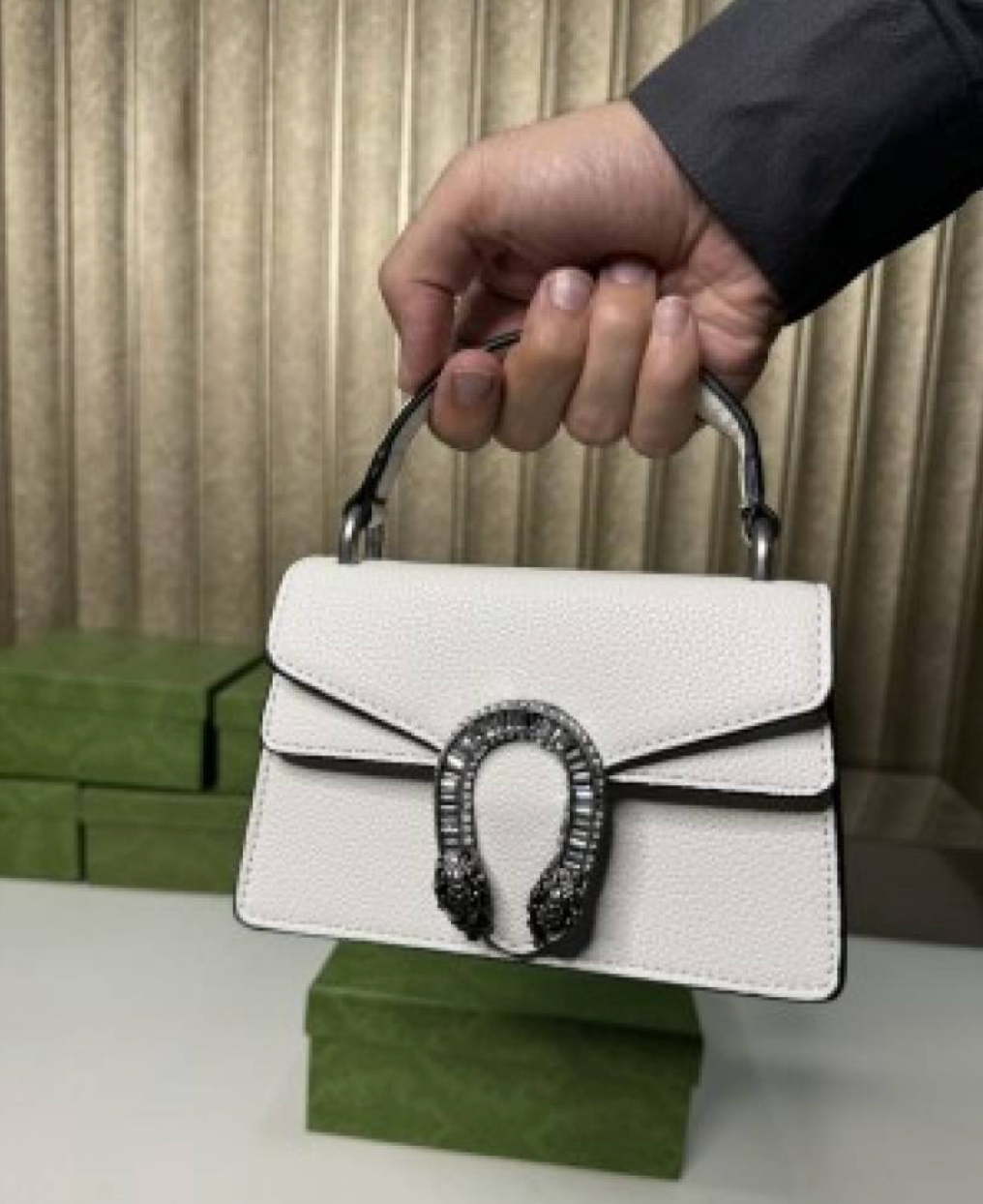 white Gucci Dionysus top handle bag with a silver-tone tiger head closure.